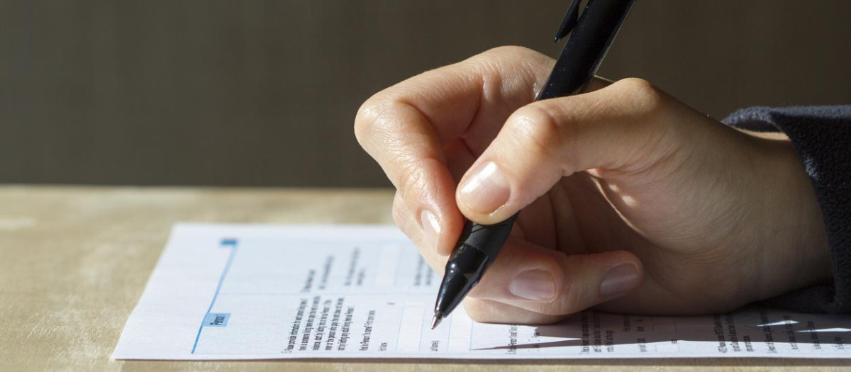 Closeup of woman's hand holding a pen filling out a census form.