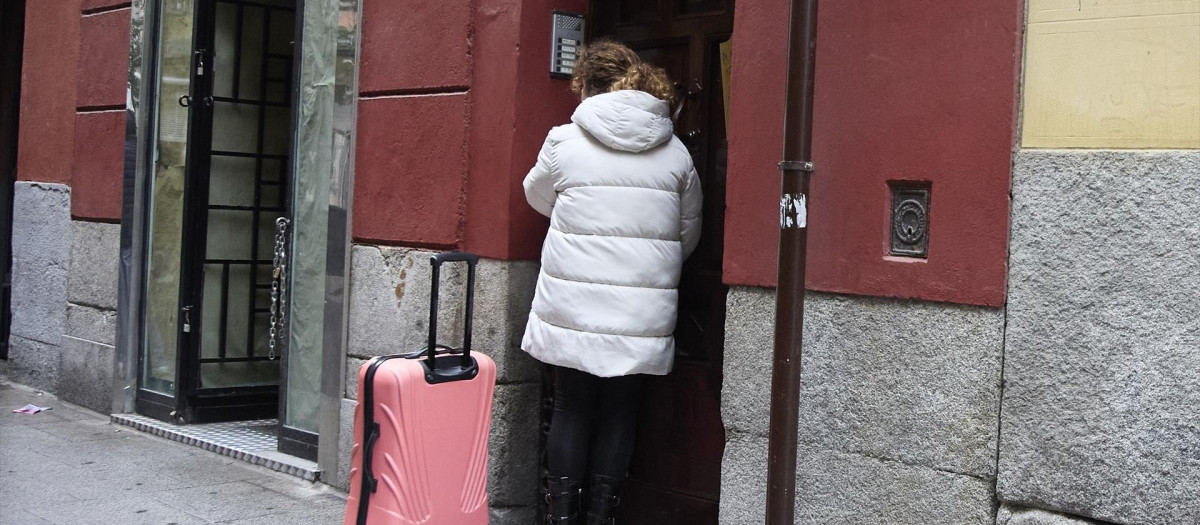 Una mujer con una maleta entra en un piso en Madrid
