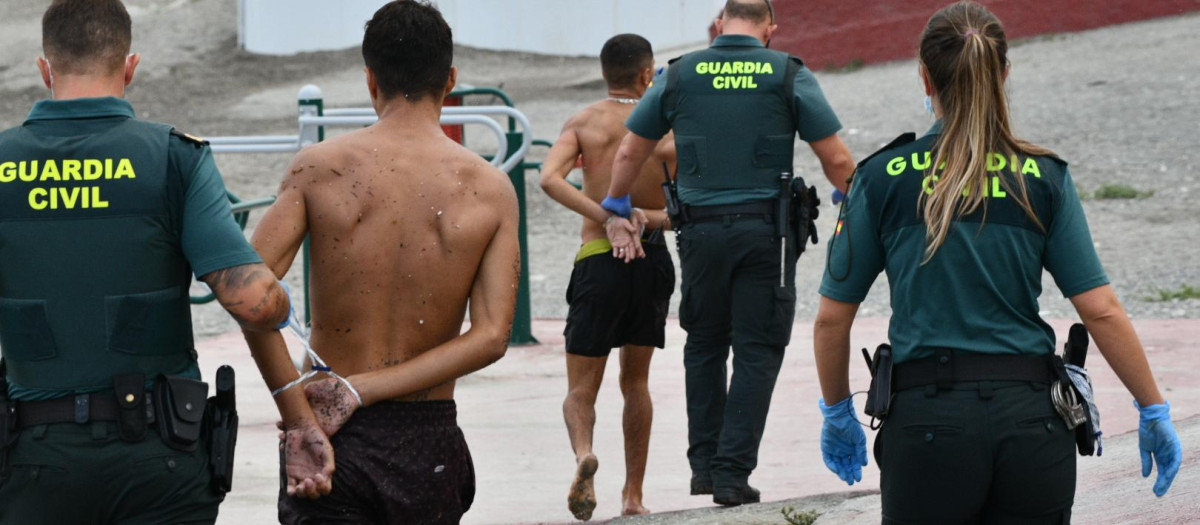 Guardias civiles con dos inmigrantes marroquíes en la playa del Tarajal de Ceuta