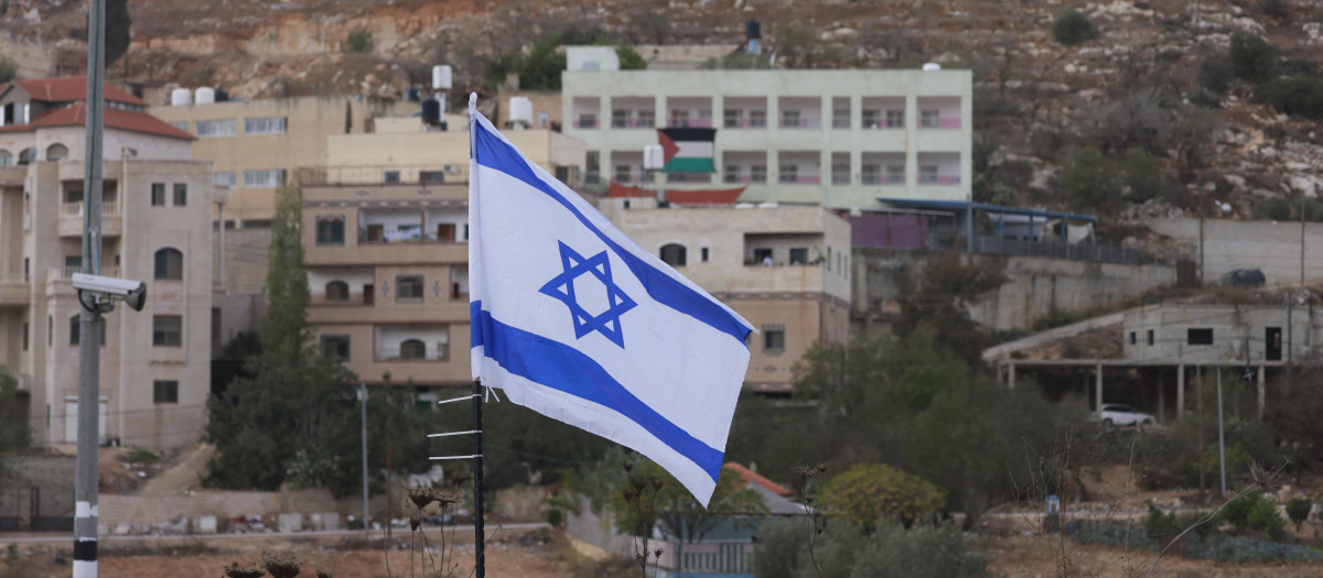 Una bandera de Israel en primer plano y una bandera de Palestina en Nablus, Cisjordania