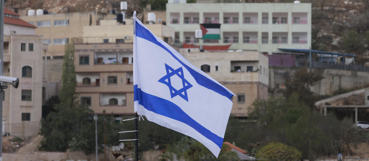 Una bandera de Israel en primer plano y una bandera de Palestina en Nablus, Cisjordania
