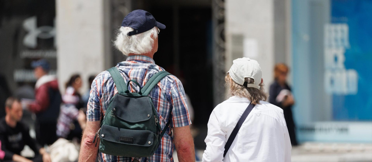 Una pareja de turistas camina en la Puerta del Sol.