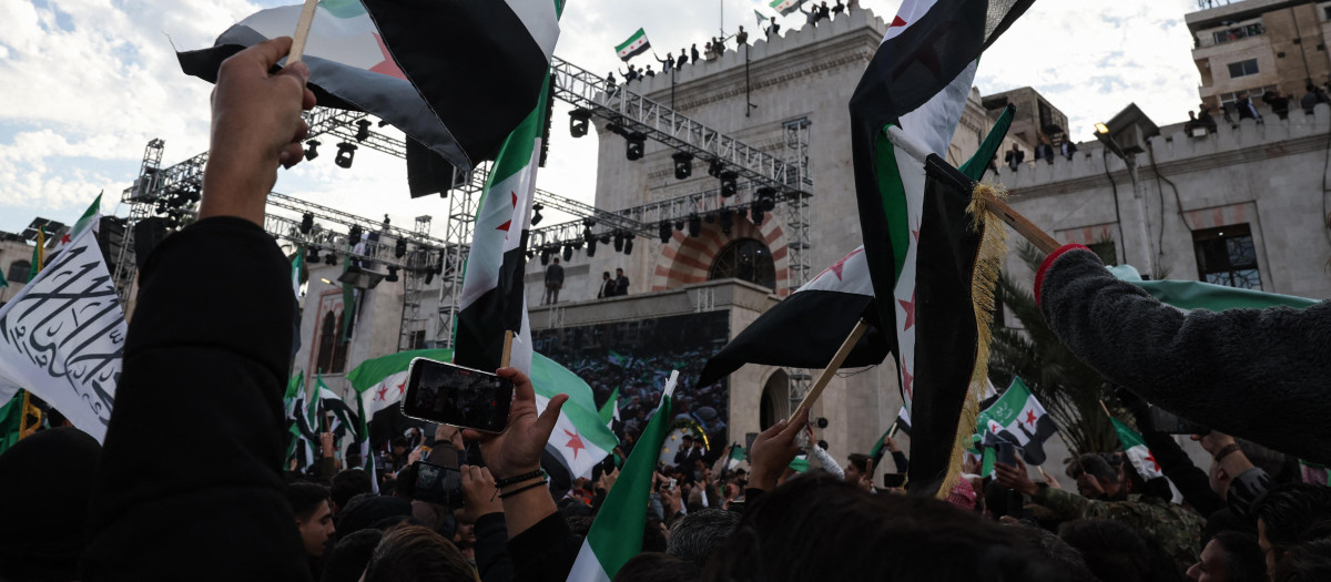 Residentes se reúnen con banderas sirias durante las celebraciones que conmemoran el primer aniversario de la ofensiva islamista que derrocó al gobernante sirio, en el centro de Hama