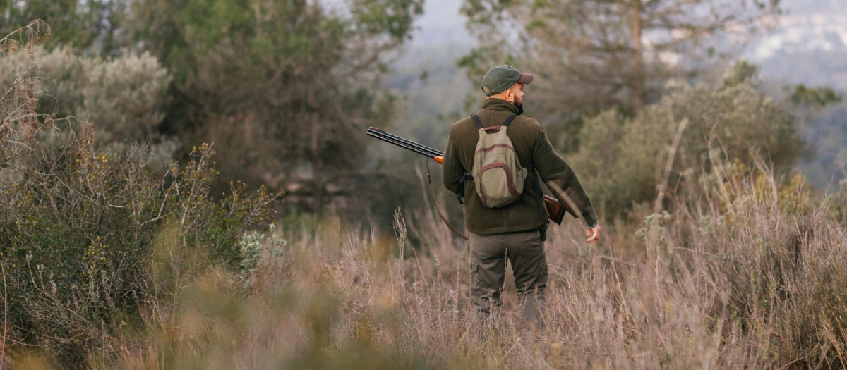 Cazador sosteniendo un arma mientras está parado en el campo