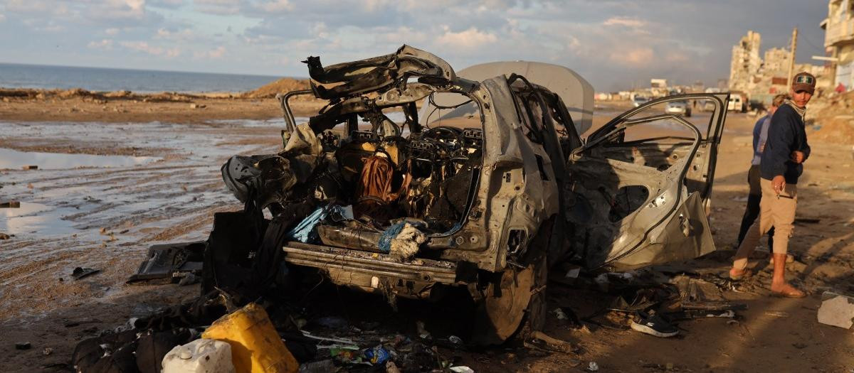 Palestinos inspeccionan el lugar de un ataque israelí contra un coche en la ciudad de Gaza