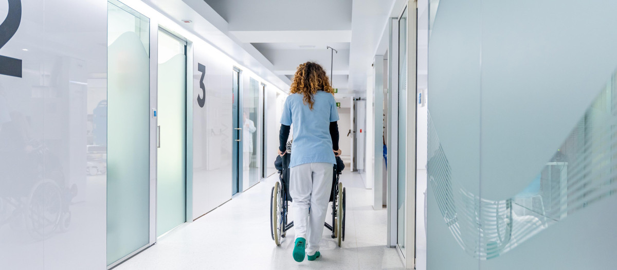 Una enfermera empujando una silla de ruedas a lo largo del hospital
