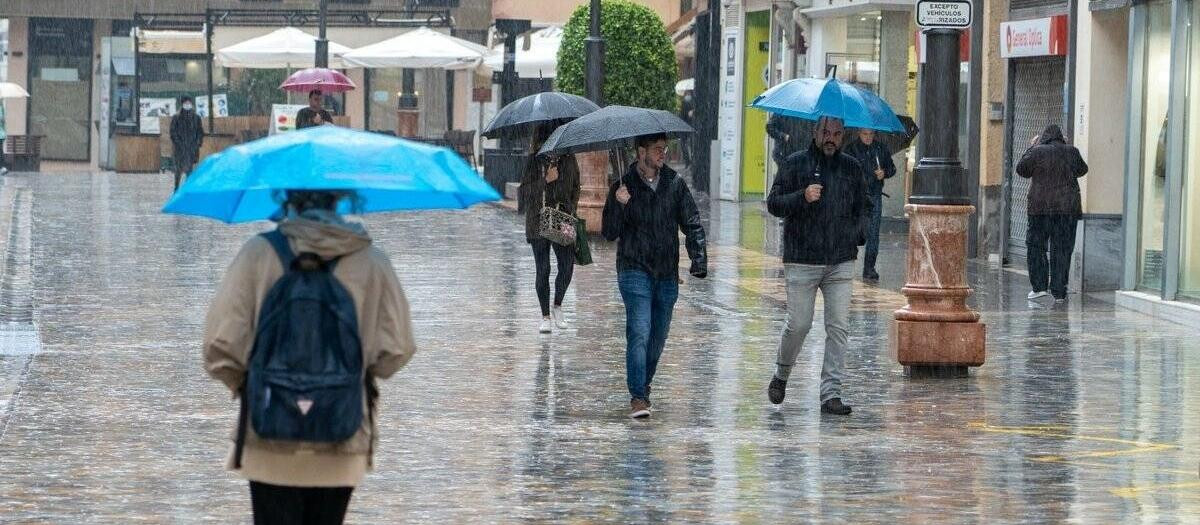 Varias personas paseando con paraguas por el centro de Cartagena