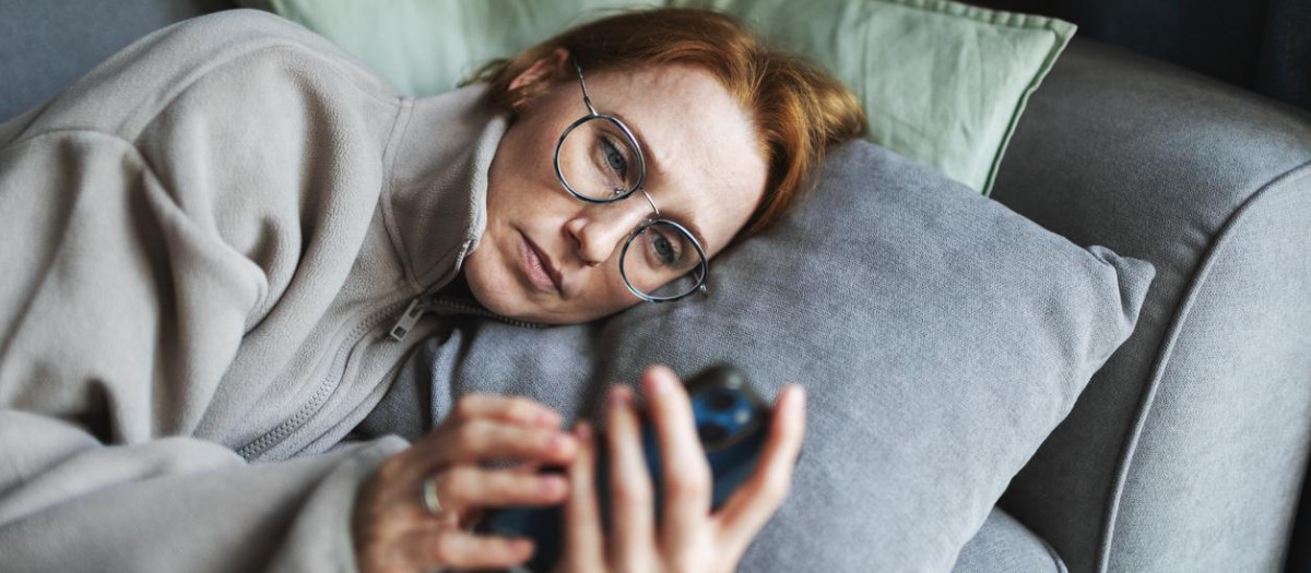 Mia adult woman lying in bed with mobile, sad and depressed, bad news