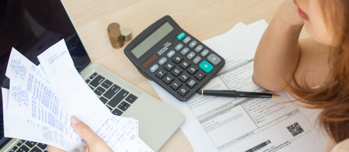 Una mujer mirando sus facturas y haciendo cálculos