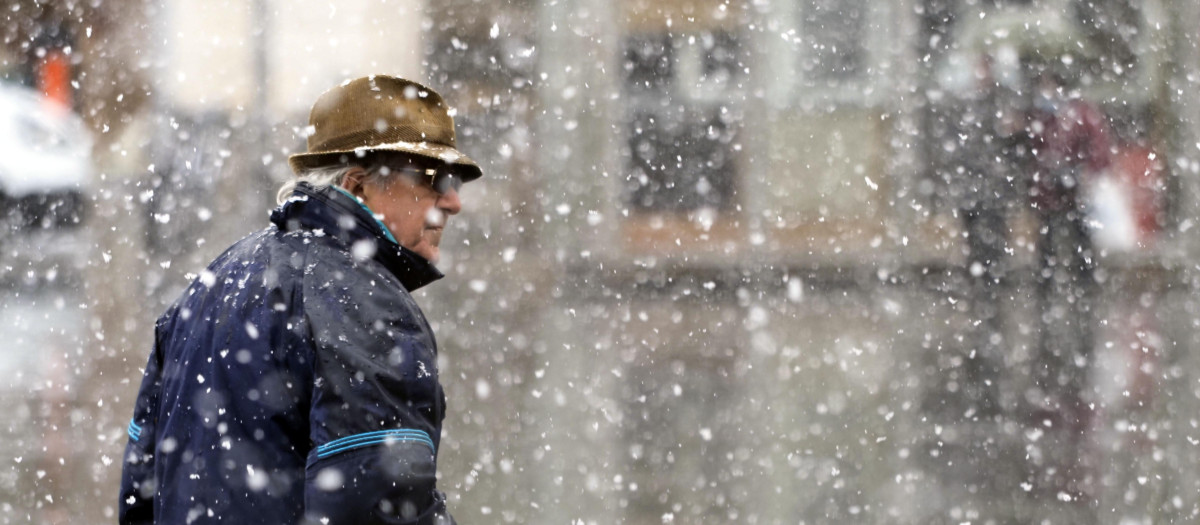 Un hombre camina bajo la nieve, en una imagen de archivo