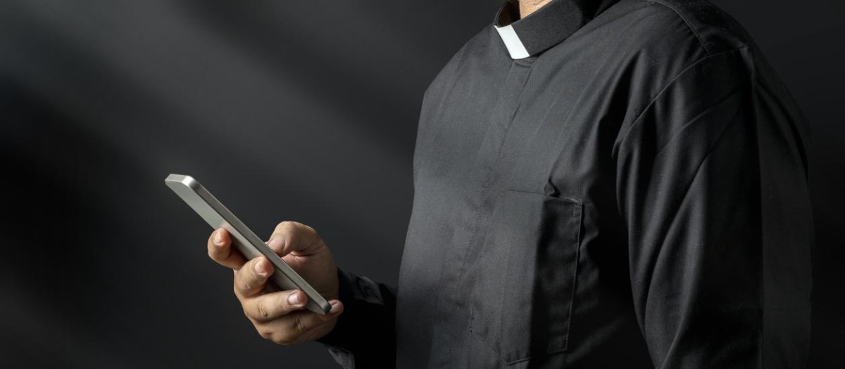 Portrait of a pastor using a mobile phone on a black background. Christian concept