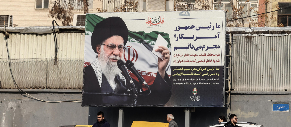 Los iraníes pasan junto a una valla publicitaria que muestra al líder supremo iraní, el ayatolá Ali Khamenei, con retórica antiestadounidense en Teherán