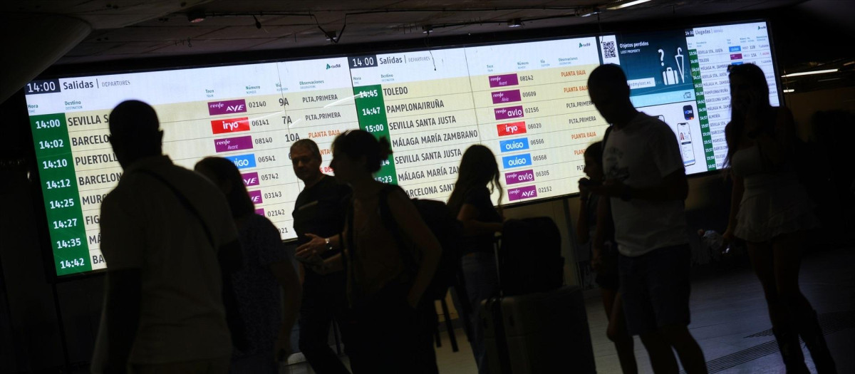 Varias personas observan las pantallas en la Estación de Atocha.