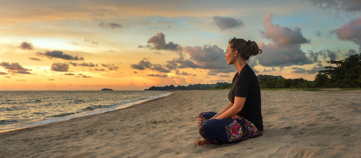 Una mujer contempla la puesta del sol desde la playa