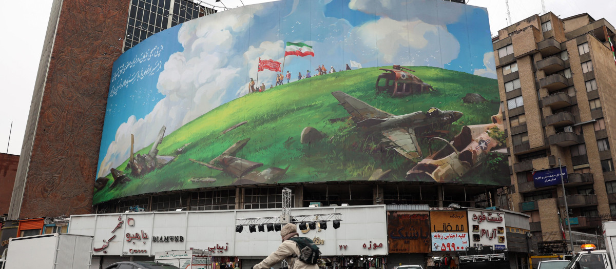 Un ciclista pasa junto a un cartel antiestadounidense en un edificio de la plaza Valiasr de Teherán