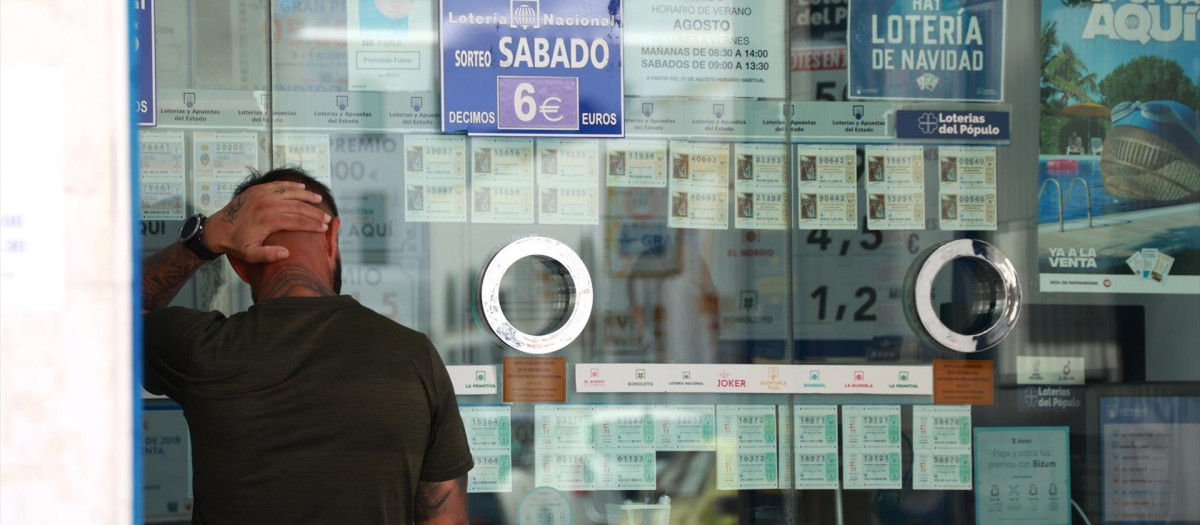 Una persona se dispone a adquirir un boleto en una Administración de Loterías