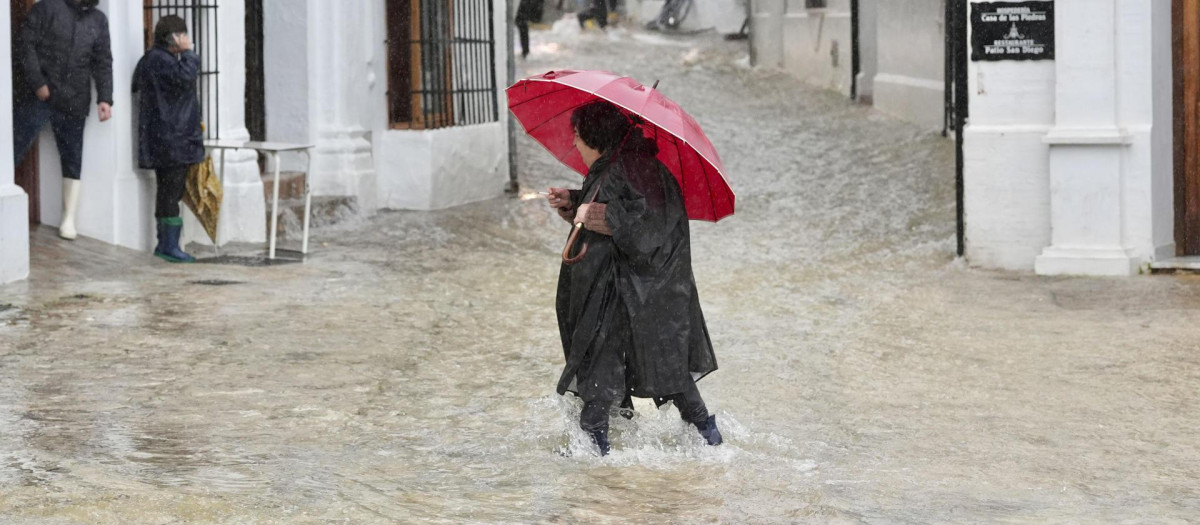 Una vecina de Grazalema (Cádiz) camina por una calle inundada