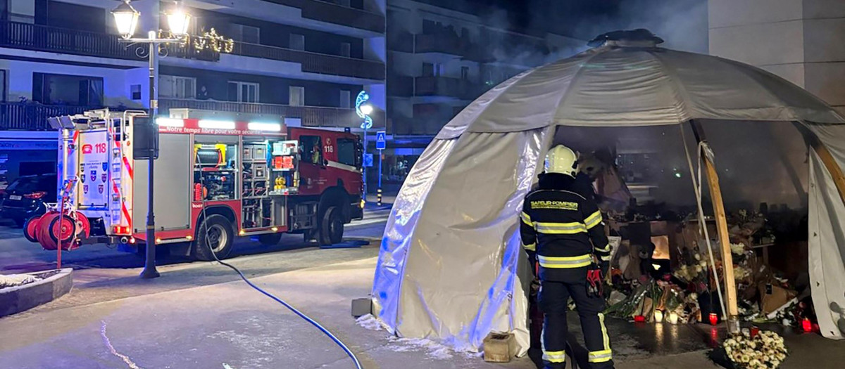 Los bomberos suizos atienden un fuego en el memorial de las víctimas del incendio en el bar Le Constellation