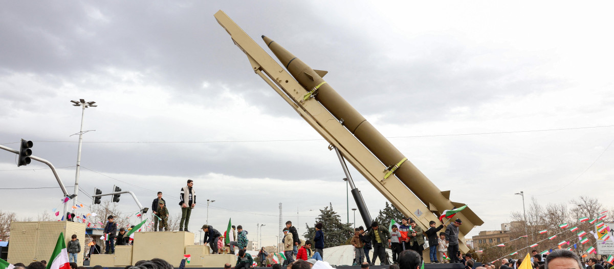 Personas caminan cerca de un vehículo de lanzamiento de misiles balísticos en Teherán