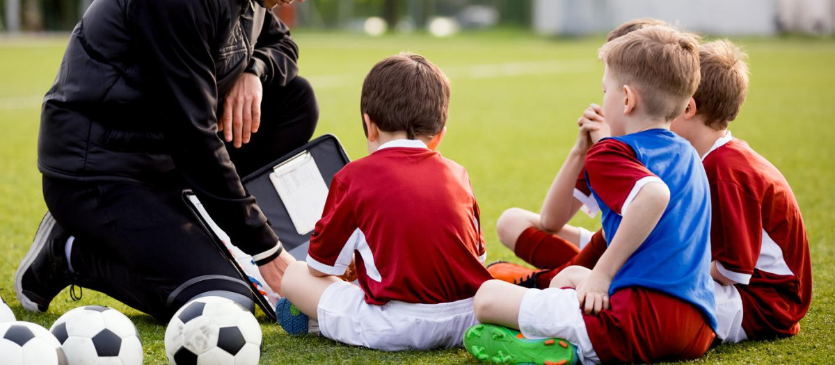 Imagen de recurso de un entrenador de fútbol base con niños