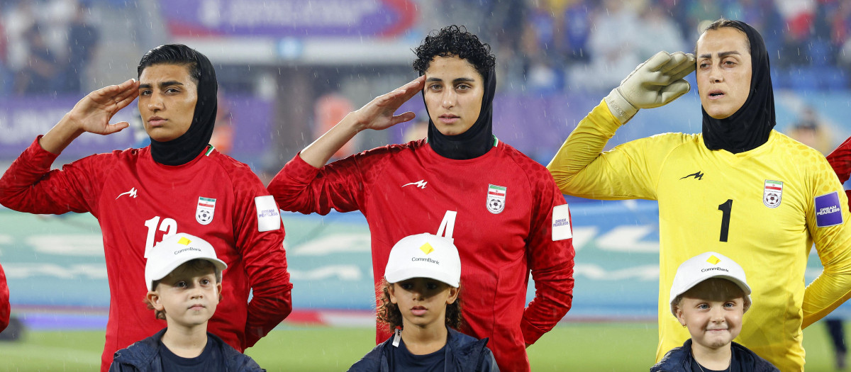 La portera Raha Yazdani y las jugadoras Melika Motevalli y Fatemeh Amineh hacen el saludo militar durante el himno nacional de Irán