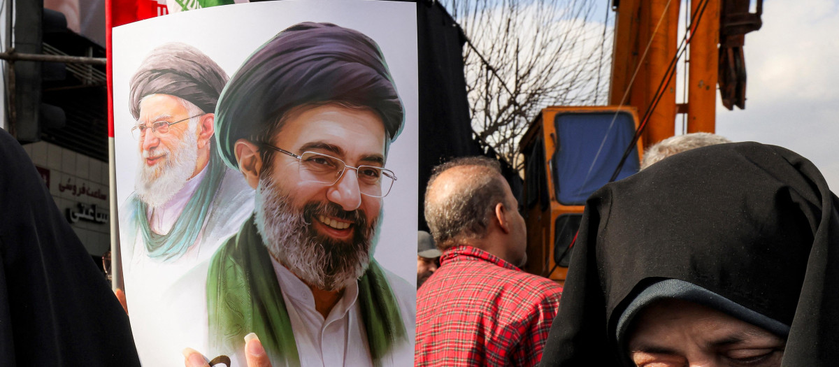 Una mujer sostiene un cartel del nuevo líder supremo de Irán, el ayatolá Mojtaba Khamenei (derecha), junto a su difunto padre, Ali Khamenei, durante una manifestación en su apoyo en la plaza Enghelab de Teherán,