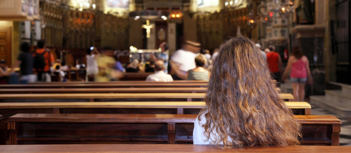 Una joven, recogida en oración en una iglesia