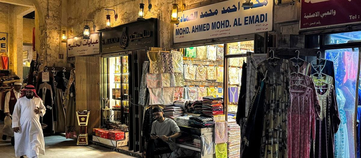 A vendor sits outside a clothing shop at a market ahead of Eid al-Fitr, the holiday marking the end of the Muslim holy fasting month of Ramadan, in Doha on March 17, 2026. (Photo by Karim JAAFAR / AFP)
