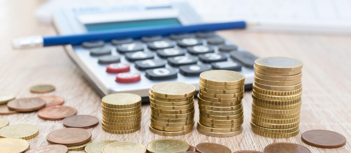 Una calculadora junto a varias monedas