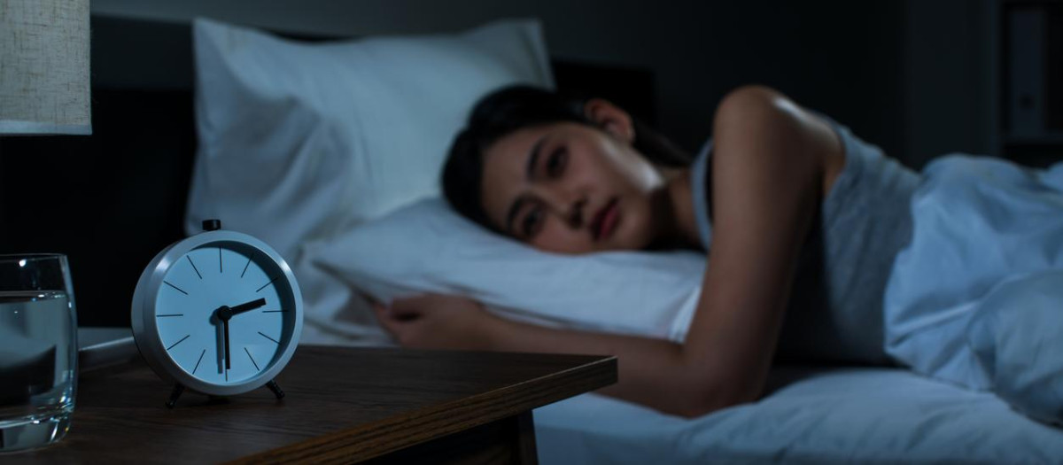 Una joven que se encuentra despierta en la cama