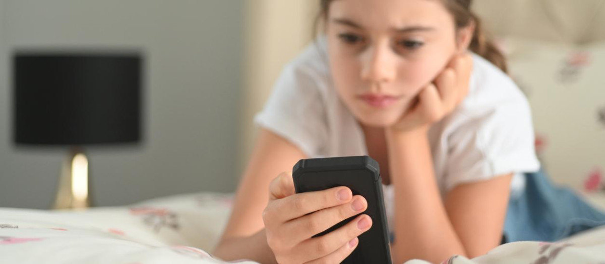 Una adolescente mira su móvil
