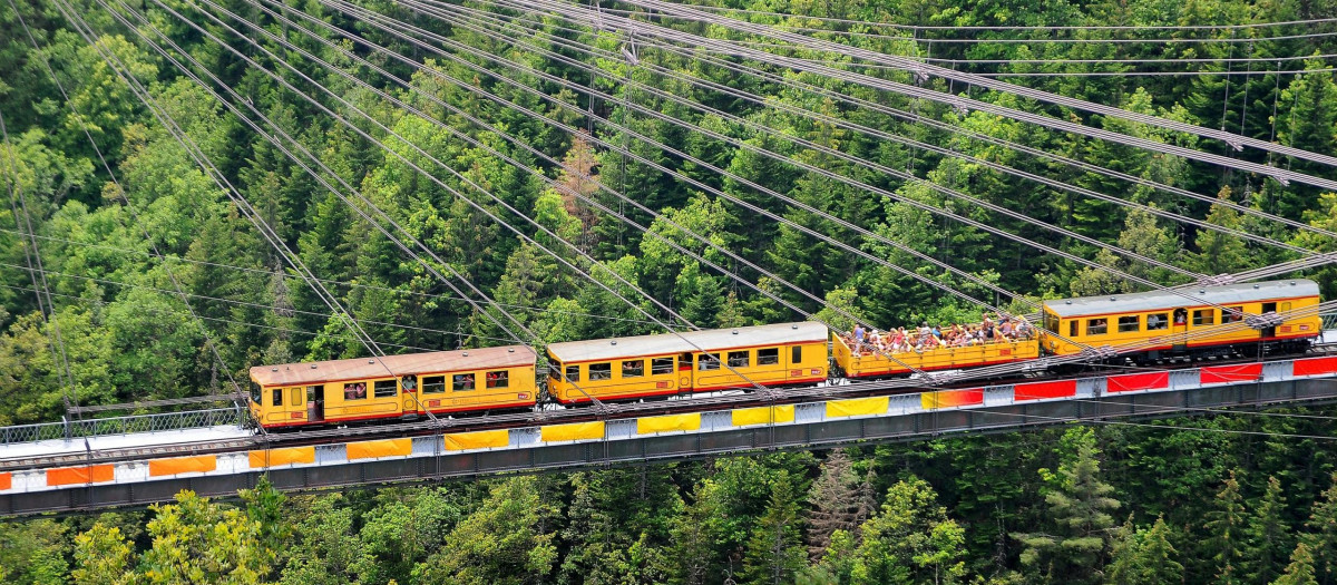 El Pequeño Tren Amarillo atraviesa un puente colgante con un vagón descapotable