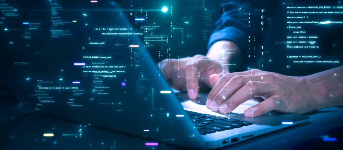 Close-up of hands typing on a laptop with glowing programming code and binary graphics, symbolizing cybersecurity technology coding or software development.