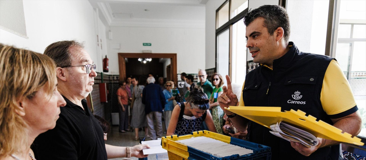 Trabajador de Correos entrega el voto por correo durante las elecciones generales de 2023 en una mesa electoral de Madrid