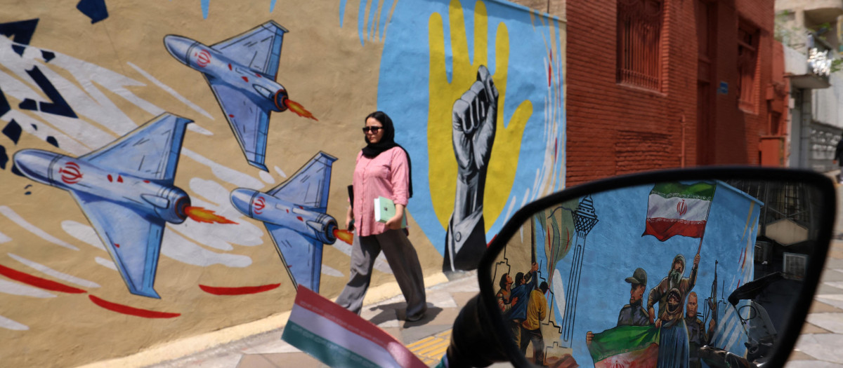 Una mujer pasa junto a un mural antiestadounidense y antiisraelí en Teherán