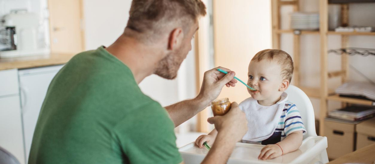 Un padre dando una papilla a su bebé