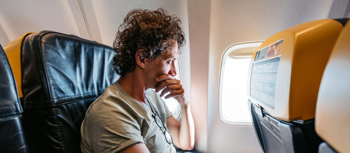 Sacred young man looking out the window of an Airplane. Having a fear of heights.