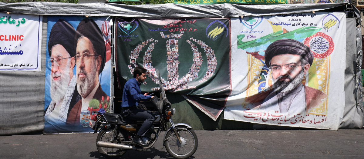 Un automovilista pasa junto a pancartas instaladas a lo largo de la carretera con imágenes del líder supremo asesinado de Irán, el ayatolá Ali Khamenei (izquierda), y del líder supremo, el ayatolá Mojtaba Khamenei, en Teherán