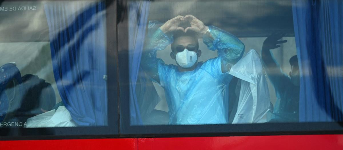 Los pasajeros del crucero MV Hondius, afectado por el hantavirus, hacen un gesto desde un autobús militar