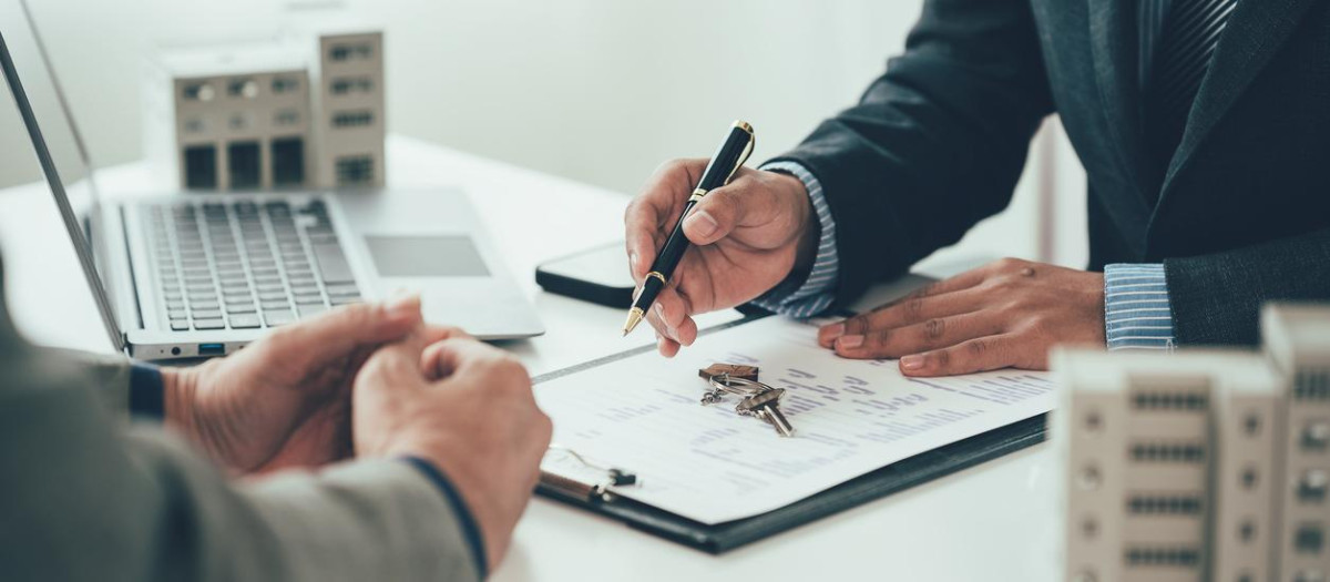 A real estate salesperson introduces a customer to a model home project and hands the keys to the customer. New home buyer approved for home loan, close-up photo