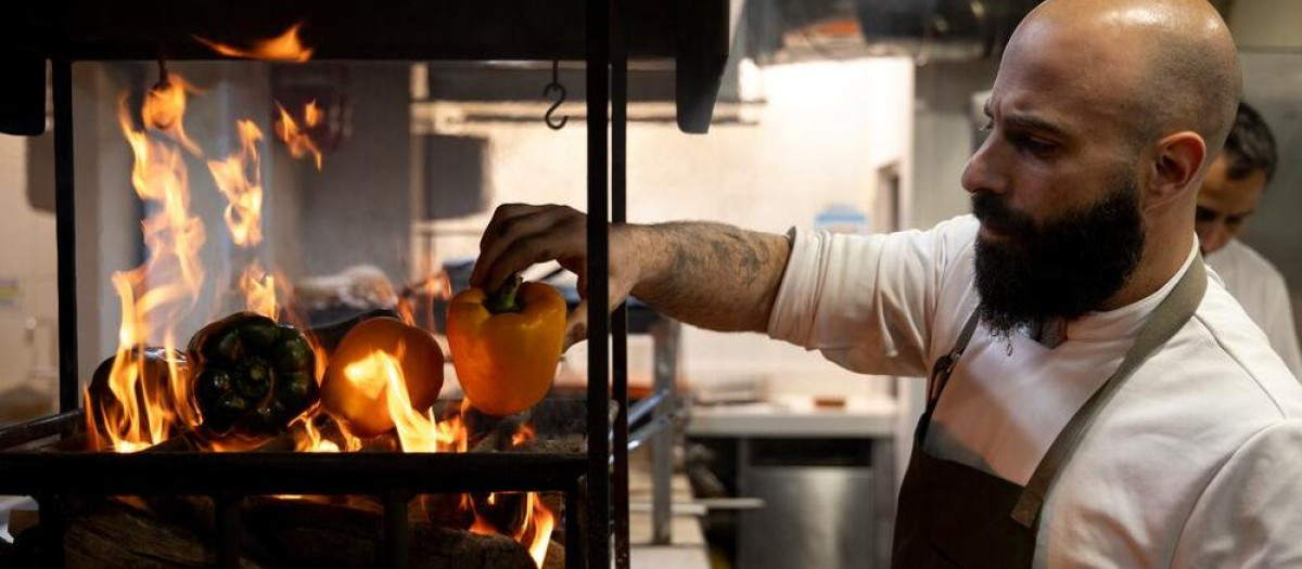 Carlos Roux, jefe de cocina de Gurisa Madrid, atendiendo unos pimientos en la brasa