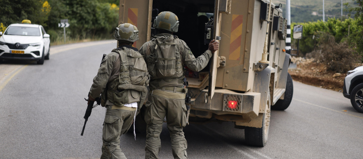 Soldados israelíes reaccionan tras ponerse a cubierto cerca de la frontera entre Israel y Líbano después de un ataque con drones de Hezbolá que impactó la frontera norte