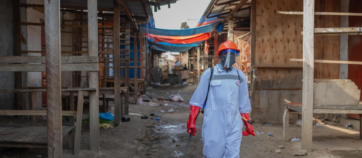 Un trabajador sanitario con equipo de protección desinfecta los puestos de un mercado de productos frescos en Bunia, provincia de Ituri, República Democrática del Congo