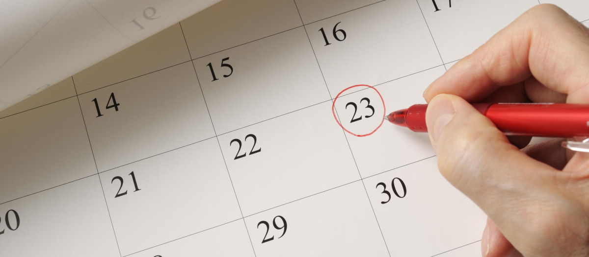 Writing a date on calendar by red pen.