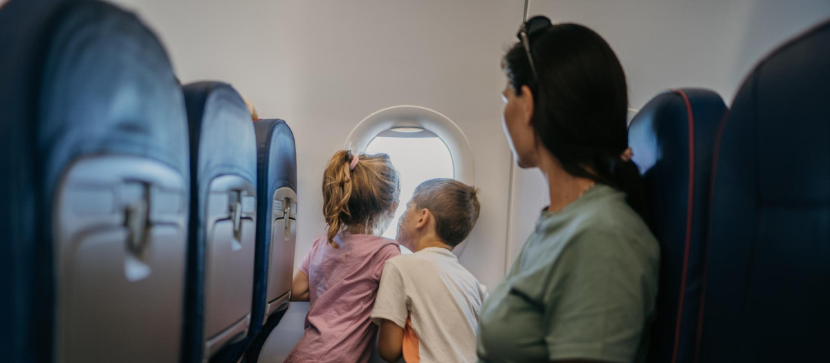 Mother with two children, son and daughter  traveling by plane, kids are looking through window