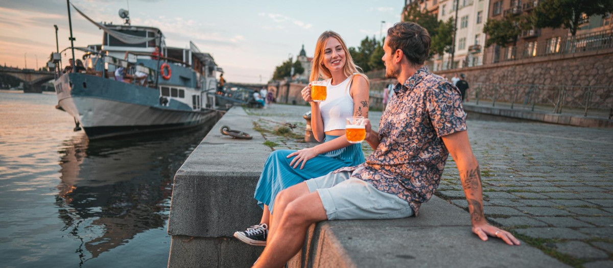 Una pareja disfruta de una cerveza checa junto al río Moldava en Praga