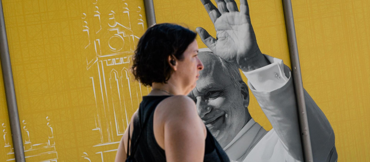Una mujer pasa por delante de un cartel publicitario del viaje apostólico del Papa León XIV a España