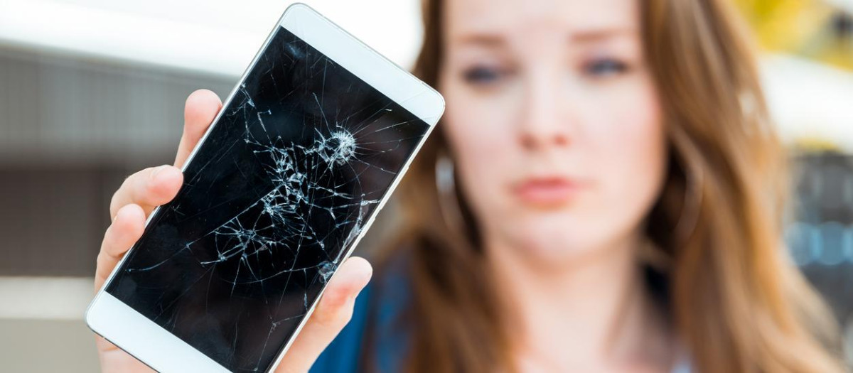 Young woman holding broken smartphone