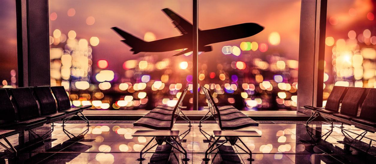 Empty airport lounge shot at night in front of the city skyline with airplane taking off against the bright lit of the city.