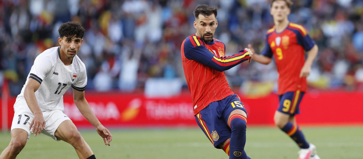 El centrocampista de la selección española de fútbol Álex Baena (d) juega un balón ante Ali Jasim, de Irak
